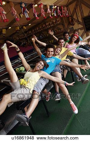 Stock Photo - Teenagers posing in front of game in amusement park. Fotosearch