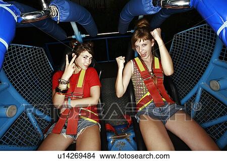 Picture - Two female teenagers on amusement park ride. Fotosearch