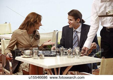 Stock Photograph - Business man and woman at cafe with laptop. Fotosearch