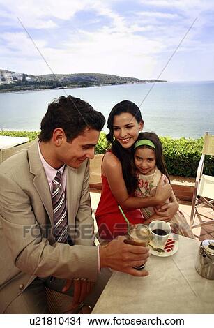 Couple with daughter at seaside cafe table View Large Photo Image Picture - Couple with daughter at seaside cafe table. Fotosearch