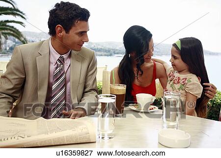Stock Photo - Couple with daughter at seaside cafe table. Fotosearch