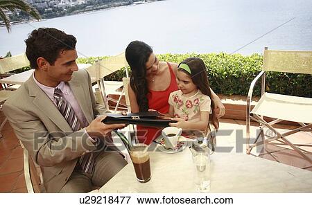 Stock Photo - Couple with daughter at seaside cafe table. Fotosearch