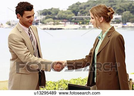 Stock Photo - Man and woman shaking hands at seaside meeting. Fotosearch