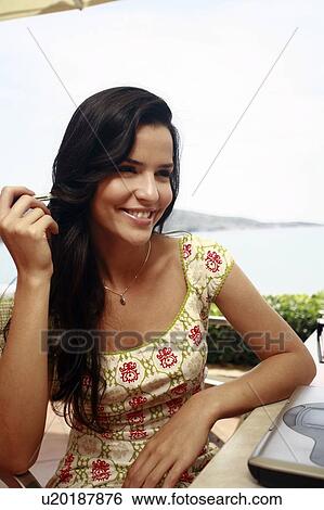 Stock Photograph - Woman at seaside table smiling. Fotosearch