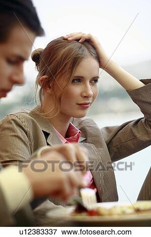 Stock Photo - Woman leaning into her hand with man eating. Fotosearch