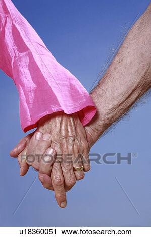 Stock Image - Closeup of senior couple holding hands. Fotosearch