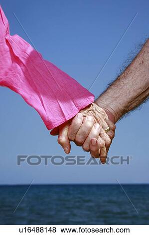 Stock Photo - Closeup of senior couple holding hands. Fotosearch