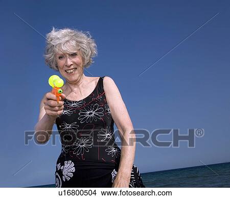 Female senior on beach with water gun View Large Photo Image Picture - Female senior on beach with water gun. Fotosearch