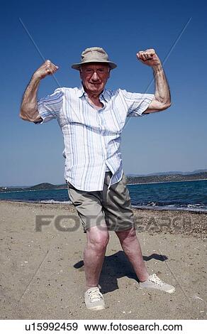 Stock Photo - Male senior showing muscles on beach. Fotosearch