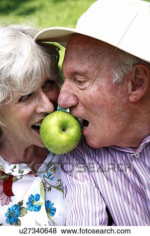 Stock Photo - Senior couple both biting apple. Fotosearch
