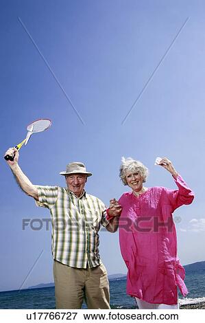 Stock Photo - Senior couple on beach with badminton racquet and ball. Fotosearch