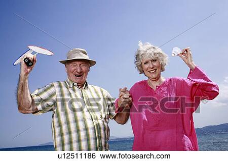 Stock Photograph - Senior couple on beach with badminton racquet and ball. Fotosearch