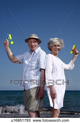 Senior couple on beach with water guns View Large Photo Image Stock Image - Senior couple on beach with water guns. Fotosearch