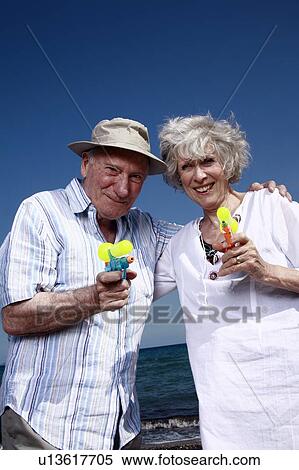 Senior couple on beach with water guns View Large Photo Image Stock Photography - Senior couple on beach with water guns. Fotosearch