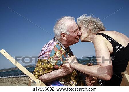 Stock Image - Senior couple with on beach kissing. Fotosearch
