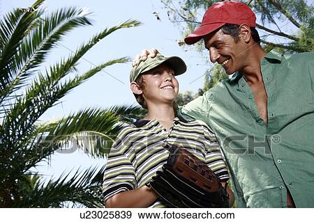 Stock Photo - Father and son with baseball caps and glove. Fotosearch