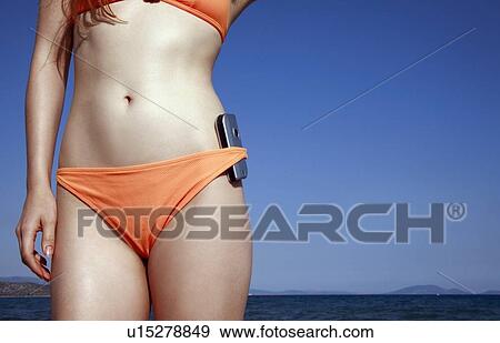 Stock Photo - Female young adult in bikini with cell phone. Fotosearch