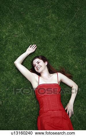 Stock Image - Female young adult lying on the grass. Fotosearch