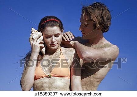 Female young adult with seashell and male young adult View Large Photo Image Stock Photo - Female young adult with seashell and male young adult. Fotosearch