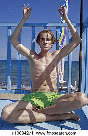 Stock Image - Male young adult doing yoga on beach. Fotosearch