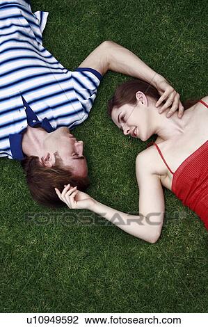 Young adult couple lying on the grass View Large Photo Image Stock Image - Young adult couple lying on the grass. Fotosearch