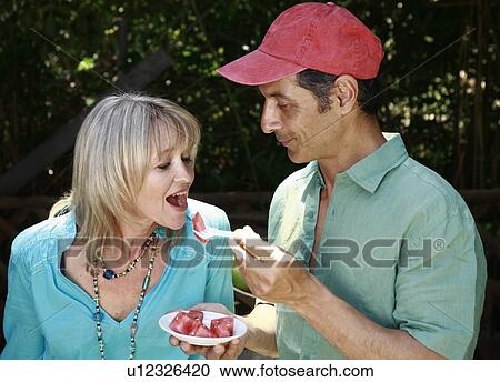 Stock Image - Mature adult couple eating watermelon. Fotosearch