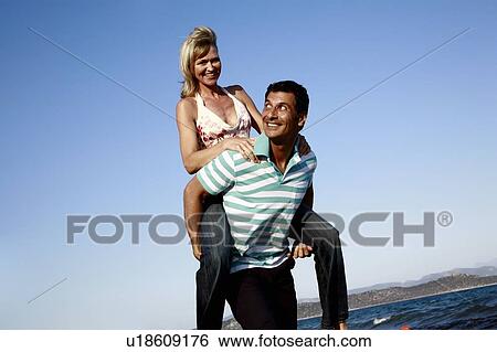 Mature adult couple piggyback on beach View Large Photo Image Stock Photograph - Mature adult couple piggyback on beach. Fotosearch