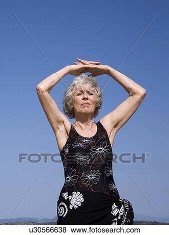 Stock Photo - Female senior stretching on beach. Fotosearch