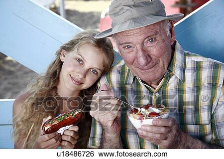Grandfather and granddaughter eating at beach View Large Photo Image Stock Photograph - Grandfather and granddaughter eating at beach. Fotosearch