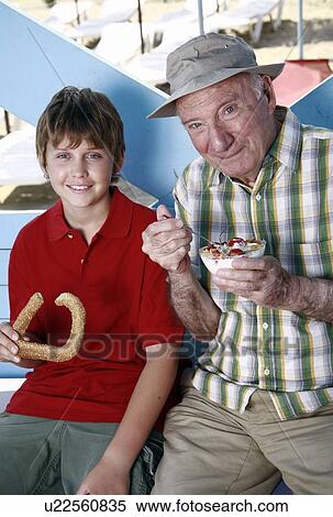 Grandfather and grandson eating at beach View Large Photo Image Stock Photography - Grandfather and grandson eating at beach. Fotosearch