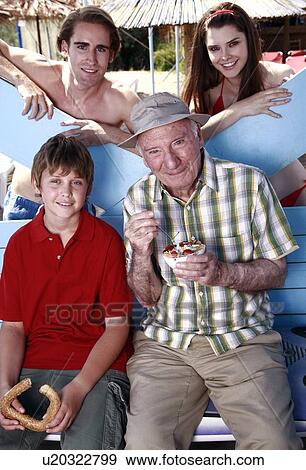 Grandfather, grandson, and young adult couple eating at beach View Large Photo Image Stock Photo - Grandfather, grandson, and young adult couple eating at beach. Fotosearch