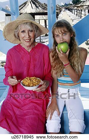Grandmother and granddaughter eating at beach View Large Photo Image Stock Photography - Grandmother and granddaughter eating at beach. Fotosearch
