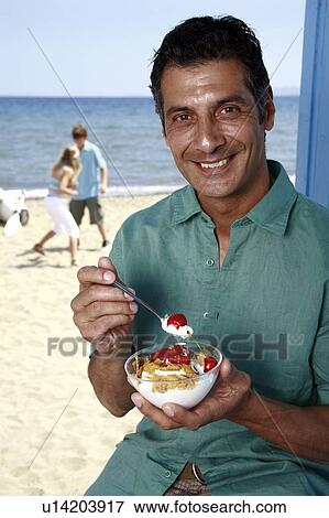 Male mature adult eating breakfast at beach View Large Photo Image Stock Photo - Male mature adult eating breakfast at beach. Fotosearch