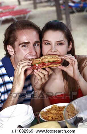 Young adult couple eating sandwich View Large Photo Image Stock Photo - Young adult couple eating sandwich. Fotosearch
