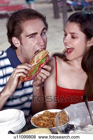 Stock Photo - Young adult couple eating. Fotosearch