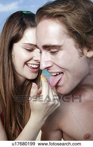 Stock Photo - Young man licking honey from young woman's finger. Fotosearch