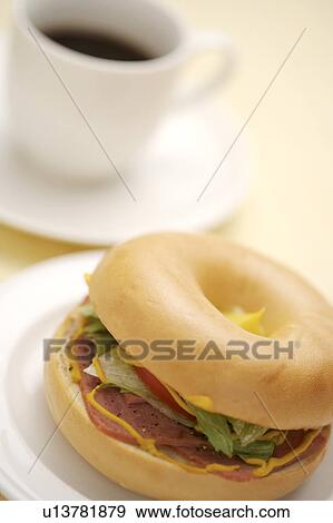 Stock Photo - Bagel on plate with cup of coffee aside. Fotosearch