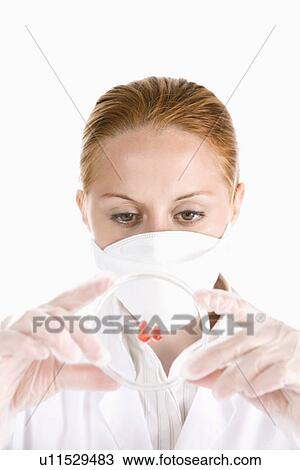 Stock Image - Female scientist looking petri dish with red drop. Fotosearch