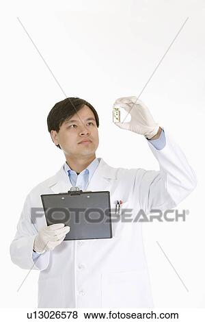 Stock Photo - One man holding up small bottle with seedling. Fotosearch