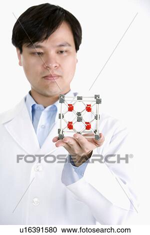 Stock Image - One man in lab coat holding molecular structure. Fotosearch