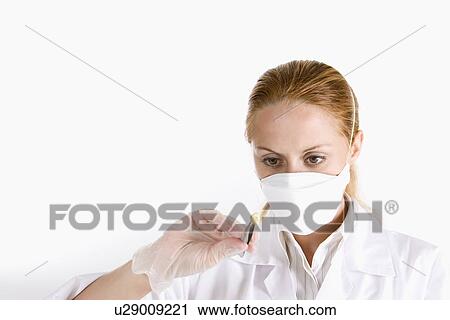 Stock Image - One woman in lab coat examining seed. Fotosearch