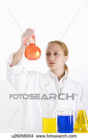 One woman in lab coat holding up flask with liquid View Large Photo Image Picture - One woman in lab coat holding up flask with liquid. Fotosearch