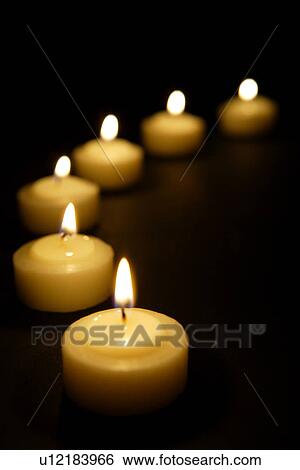 Stock Photograph - Lit candles in a row. Fotosearch