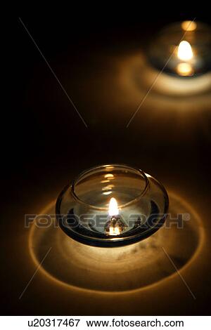 Stock Photo - Lit candles in candle holders. Fotosearch