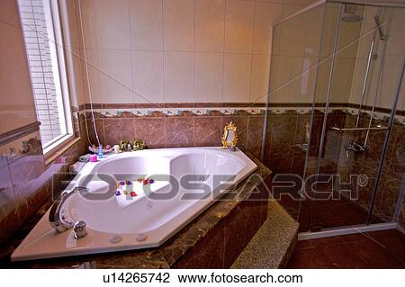 Stock Image - Bathtub with petals by window. Fotosearch