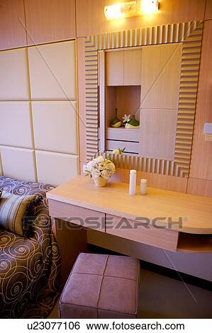 Stock Photograph - Close-up of a make-up table with mirror and chair by bed. Fotosearch