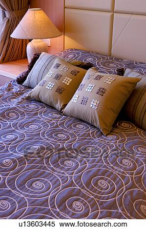 Stock Photography - Close-up of bed with pillows and quilt by side table with lamp. Fotosearch