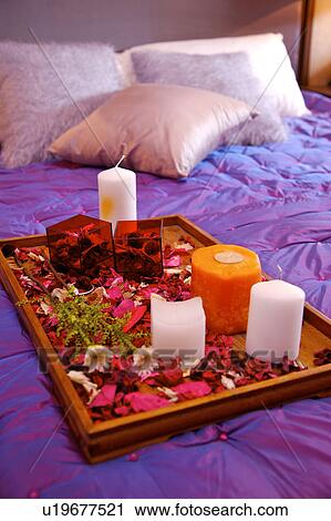 Stock Image - A tray of flowers and candles on bed, close-up. Fotosearch