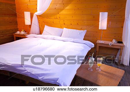 Stock Image - Bedroom, two glasses of drinks on the bedside table. Fotosearch