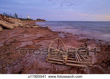 Stock Image - Point Prim lighthouse and old lobster trap, sunset, Prince Edward Island, Canada. Fotosearch